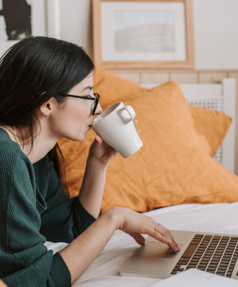 woman sipping on tea while browsing on her laptop